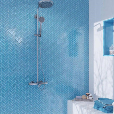 Cerulean blue glossy glass mosaic tile wall in shower with vibrant blue color and herringbone pattern